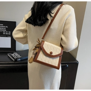 Détail d'un sac bandoulière matelassé chic avec garniture en cuir marron et breloque lapin