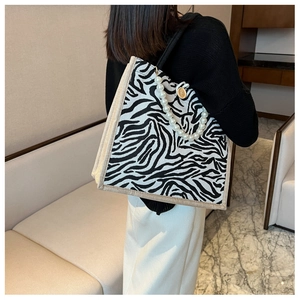 Detail of zebra pattern tote bag with pearl handle and wooden button closure