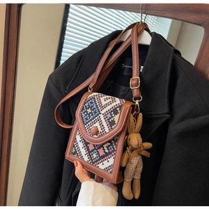 Detailed view of ethnic woven crossbody bag with brown leather trim and cute bunny charm
