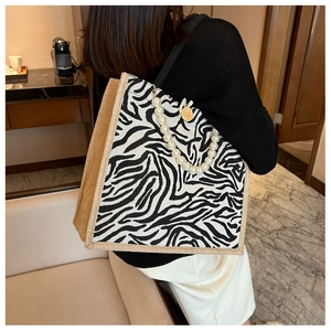 Detail of zebra pattern tote bag with large pearl chain handle in modern room setting