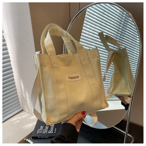 Detailed macro of beige canvas tote bag with FASHION patch and sturdy shoulder strap