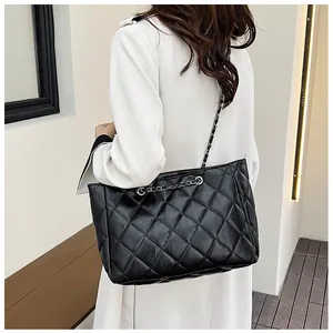 Close-up of black quilted leather tote bag with silver metal chain shoulder strap