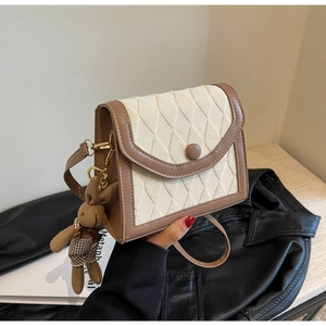 Détail du sac à bandoulière matelassé beige avec bordure en cuir marron et breloque lapin