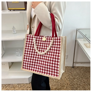 Detail of red houndstooth tote bag featuring pearl chain and wooden button closure