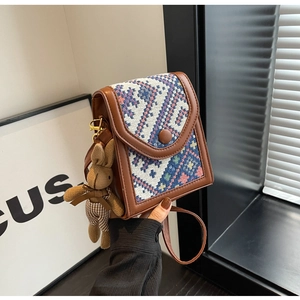 Ethnic woven crossbody bag with brown leather trim and a cute plush rabbit charm