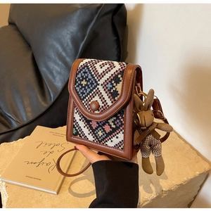 Detail of vintage knit crossbody bag featuring colorful patterns and a rabbit charm