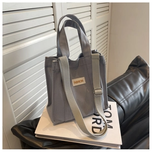 Close-up of gray canvas tote bag with FASHION label on a white book in a modern room