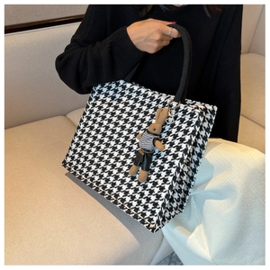 Detail of checkered tote bag with woven texture and a cute rabbit plush accessory
