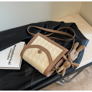 Détail d'un sac bandoulière matelassé chic avec garniture en cuir brun et breloque lapin