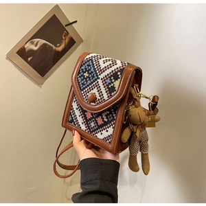 Detailed view of bohemian crossbody phone bag with woven geometric pattern and teddy charm