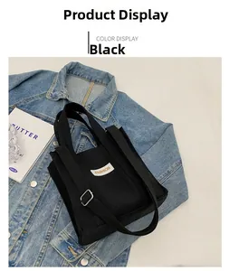 Detailed view of black canvas square tote with adjustable strap on a denim jacket