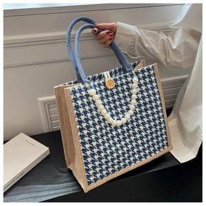 Detail of houndstooth tote bag featuring pearl chain strap and natural jute texture