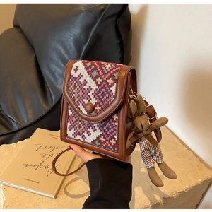 Detailed close-up of ethnic patterned crossbody bag with cute rabbit charm and brown leather