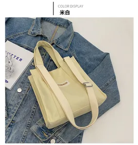 Detailed top view of off-white canvas tote bag with FASHION label on denim background
