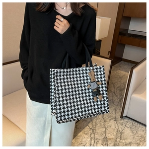 Detail of black and white houndstooth tote bag with brown bear charm for daily commute