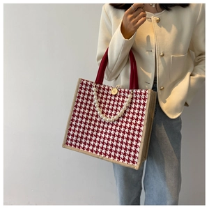 Detail of red houndstooth tote bag featuring elegant large pearl handles and wood button