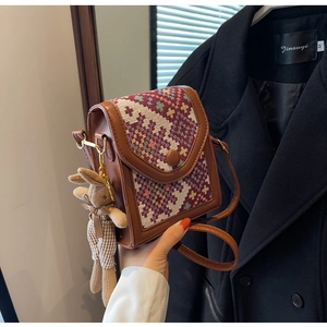 Close-up of brown crossbody bag with ethnic geometric pattern and rabbit charm