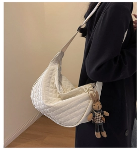 Détail d'un sac à bandoulière matelassé beige avec un joli pendentif lapin en peluche