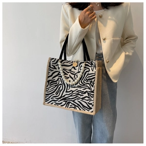 Detail of zebra pattern tote bag featuring large pearl strap and wooden button closure