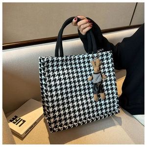Close-up of black and white houndstooth tote bag with a cute rabbit doll pendant