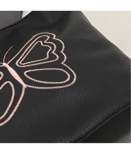 Detailed close-up of pink butterfly embroidery on black leather vintage tote bag