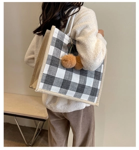 Detail of waffle pattern tote bag with plush balls on a model's shoulder for casual use