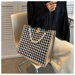 Detail of houndstooth tote bag featuring elegant pearl handles and wooden button closure