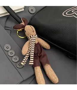 Detailed close-up of a knitted rabbit charm with metal ring on a black leather tote bag