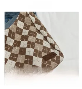 Detail of checkered canvas bag with leather FASHION tag and vintage brown pattern