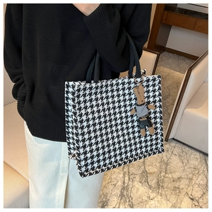 Detail of houndstooth tote bag featuring a cute rabbit charm and woven handles