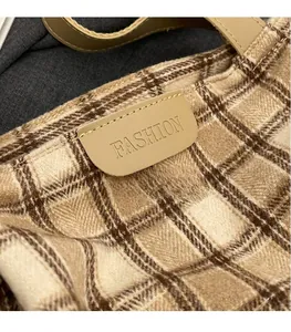Close-up of the FASHION leather tag on a beige and brown checkered knit tote bag