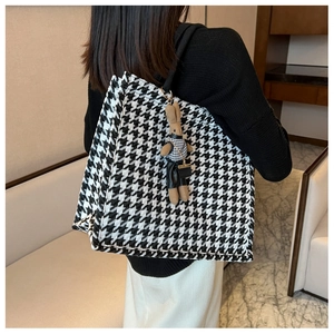 Detail of large houndstooth tote bag with a cute knit bunny charm on a shoulder strap