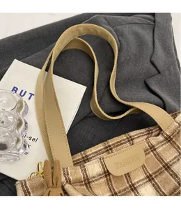 Detail of wool plaid tote bag featuring a leather fashion label and a cute brown rabbit charm
