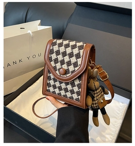 Close-up of vintage houndstooth crossbody bag with a rabbit charm in a gift box setup