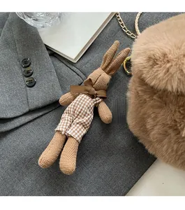 Close-up of a brown knitted rabbit charm with plaid overalls on a grey suit jacket