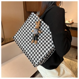 Detail of classic houndstooth tote bag with a brown plush rabbit doll charm accessory