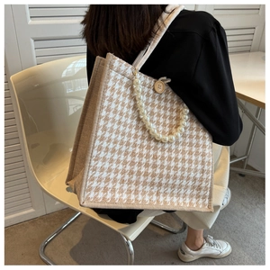Macro detail of houndstooth tote bag featuring pearl chain strap and wooden button closure