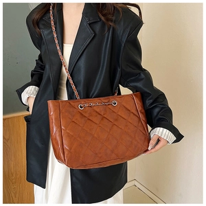 Caramel brown quilted tote bag with silver chain strap worn with a black leather jacket