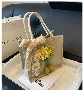 Detailed close-up of beige jute handbag with lace bow and crochet floral charms