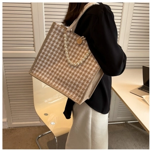 Detail of houndstooth tote bag featuring a pearl handle and vintage wooden button