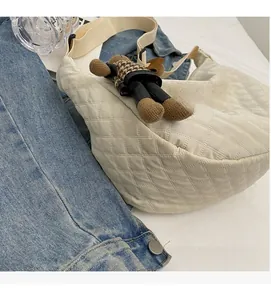 Détail d'un sac bandoulière blanc matelassé avec un petit pendentif ours décoratif