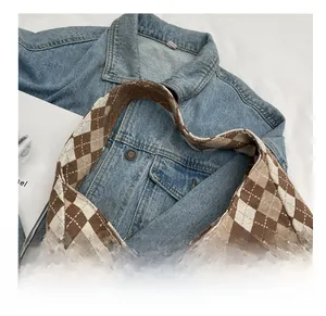 Detail shot of the checkered canvas bag showing wide shoulder strap and fabric texture