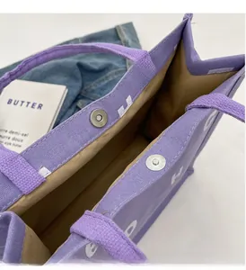 Detail of purple canvas tote bag featuring silver magnetic snap closure and thick fabric texture