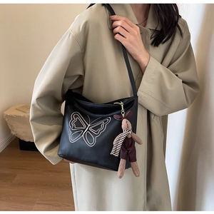 Detail of black butterfly embroidered hobo bag with cute rabbit plush keychain accessory