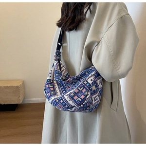 Detail view of ethnic dumpling bag with geometric pattern and adjustable strap on a model