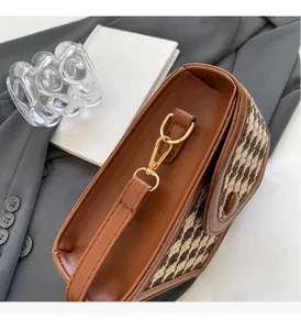 Detail of brown leather bag with houndstooth fabric side panel and gold hardware