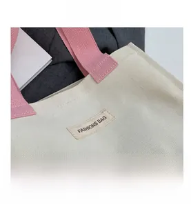 Gros plan détaillé du sac cabas en toile crème avec anses roses et étiquette tissée