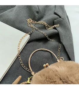 Detail of plush faux fur bag with engraved gold metal ring handle and chain strap