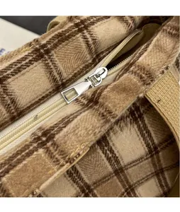Close-up of silver metal zipper and brown plaid wool fabric on large shoulder bag