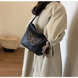 Detail of black tote bag with pink butterfly embroidery and a plush rabbit charm